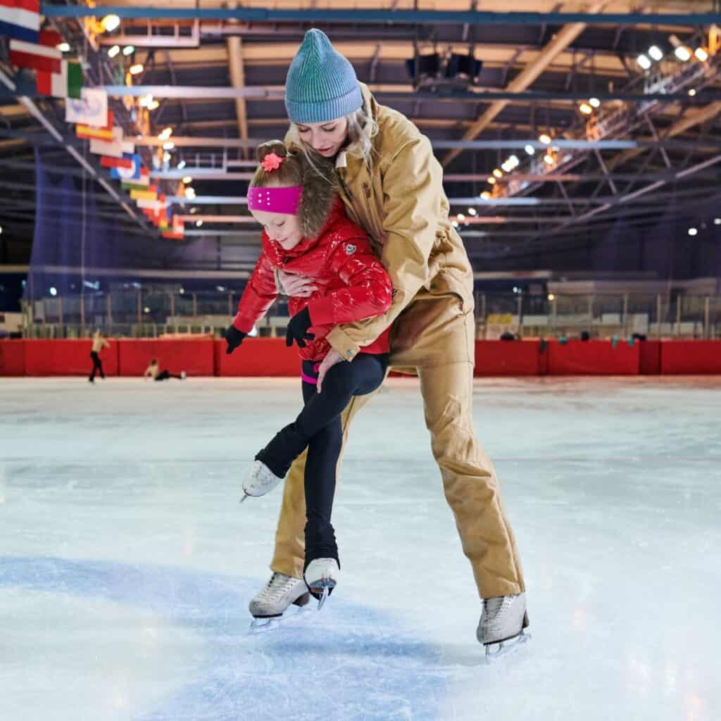 Woman teaching a young girl how to figure skate