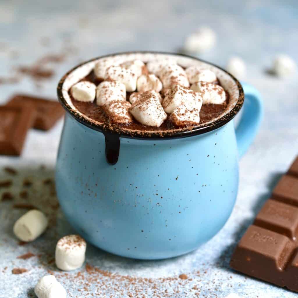 A blue mug filled with hot chocolate and marshmallows