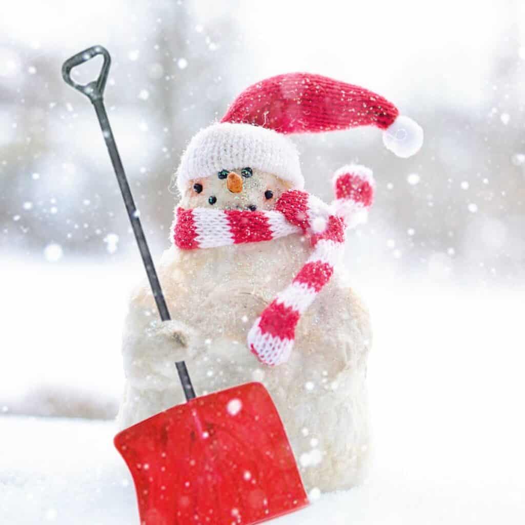 Snowman holding a red and black shovel